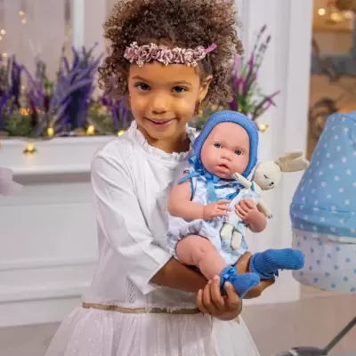 Menina com vestido branco e coroa cor-de-rosa segura boneca vestida de azul com coelho de pelúcia