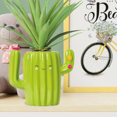 Vaso de cerâmica verde em forma de cacto sorridente com planta artificial