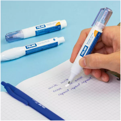 Canetas corretoras MILAN brancas e azuis sobre mesa azul e folha quadrícula.