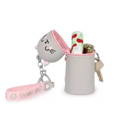 Porta-chaves em silicone cinzento com interior rosa e formato de cabeça de gato, lábios hidratante e chave num fundo branco.
