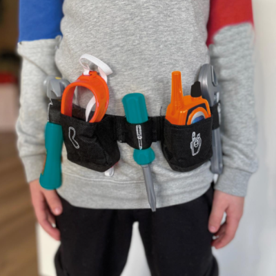 Cinto de ferramentas de brinquedo coloridas em tecido preto com camisola cinzenta e mangas azul e vermelha