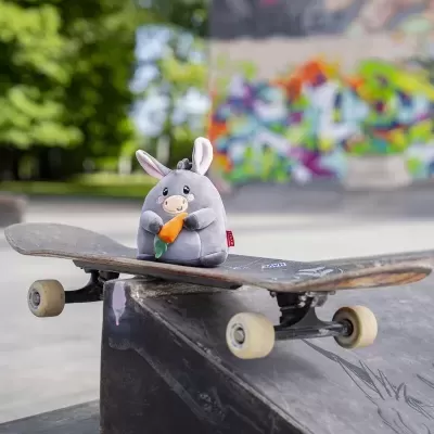 Pelúcia de coelho cinzento segurando cenoura em skate no parque