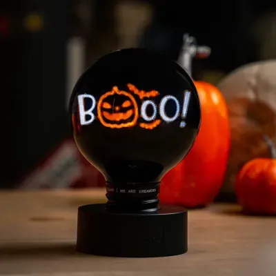 Lâmpada decorativa preta com luzes LED que formam a palavra BOO e abóbora laranja
