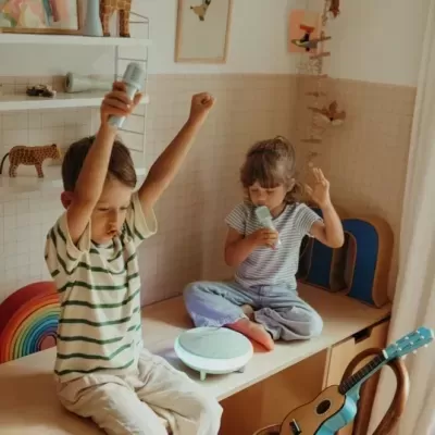Crianças a brincar com microfones numa sala infantil bem decorada.
