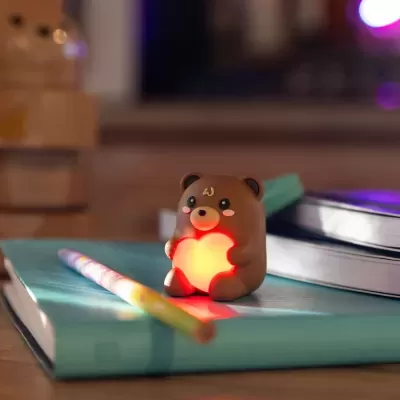 Urso decorativo a segurar coração iluminado sobre livros