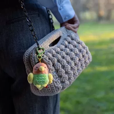 Mala bege de crochê com pendente de pássaro de peluche