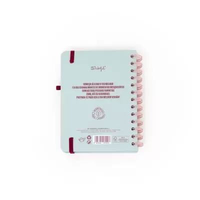 Caderno azul claro com argolas cor-de-rosa e elástico vermelho com texto inspirador