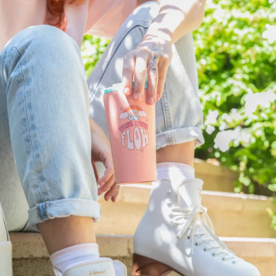 Pessoa sentada segurando copo rosa claro com texto JUST YOUR FLOW