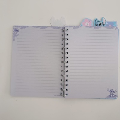 Caderno espiral aberto com folhas pautadas e abas coloridas de personagens.