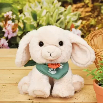 Peluche de coelho creme com lenço verde sentado numa mesa de madeira