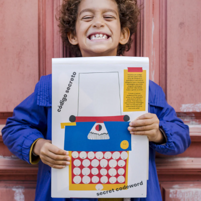 Criança segurando papel com ilustração de máquina de escrever e texto em português e inglês