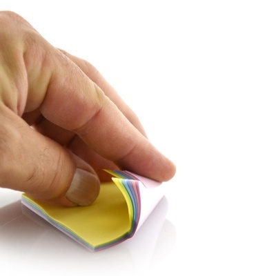 Mão a descolar nota autocolante amarela de bloco multicolor