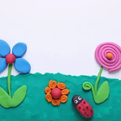 Flores e uma joaninha feitas de plasticina colorida sobre fundo branco