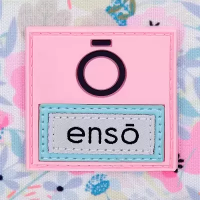 Etiqueta rosa com texto 'ensō' em tecido e símbolo preto num fundo floral pastel