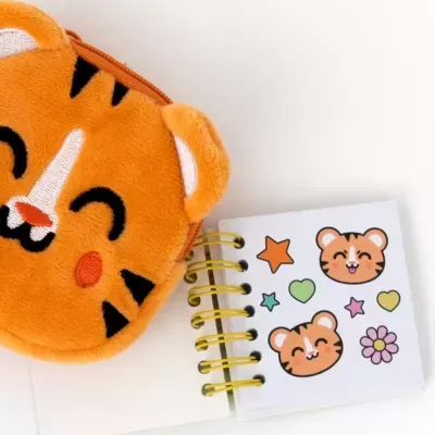 Estojo de peluche laranja e caderno com desenhos de tigre e símbolos coloridos