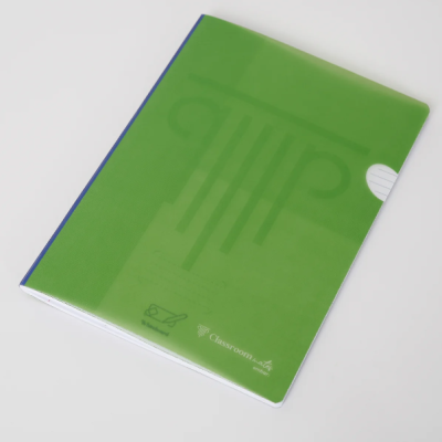 Caderno com capa verde translúcida e lombada azul sobre superfície branca