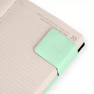 Caderno aberto com marcador magnético verde-menta LEGAMI nas páginas.