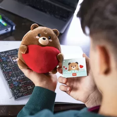 Urso de pelúcia castanho com coração vermelho e cartão ilustrado