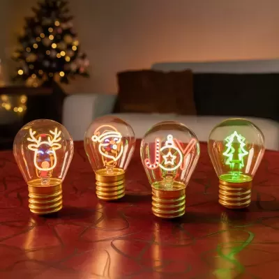 Quatro lâmpadas decorativas de Natal com filamentos iluminados em formas festivas, sobre mesa vermelha