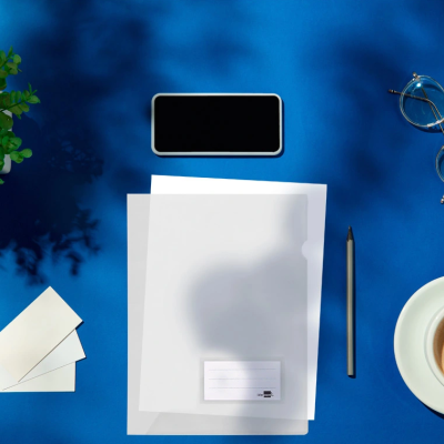 Área de trabalho com papel, smartphone, lápis, óculos, cartões, café e planta