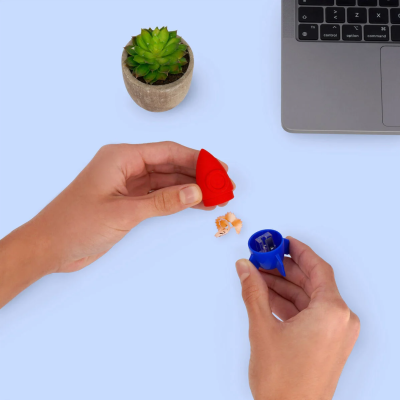 Apontador em forma de foguete vermelho e azul junto a planta e teclado