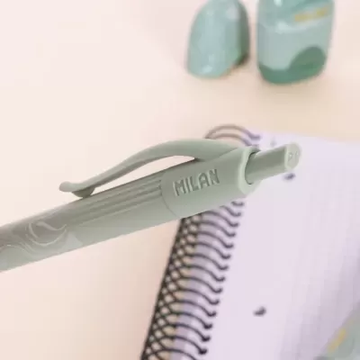 Caneta MILAN verde claro com caderno de espiral ao fundo