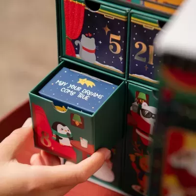 Caixa verde com gaveta azul e texto 'MAY YOUR DREAMS COME TRUE', ilustrações de pinguim e coelho