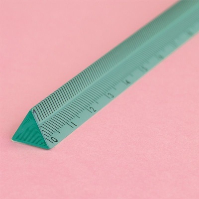 Régua triangular verde com marcações em centímetros sobre fundo rosa