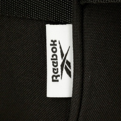Etiqueta branca com logótipo e texto REEBOK em tecido negro
