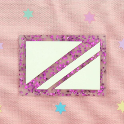 Cartão postal com glitter roxo em moldura transparente sobre tecido rosa com estrelas coloridas