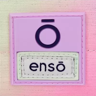 Etiqueta roxa e branca com texto 'ensō' em superfície cor-de-rosa