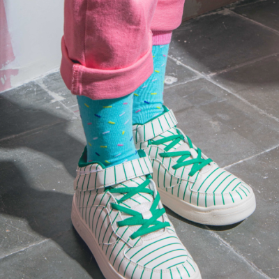 Tênis brancos e verdes com meias azuis coloridas e calças rosa