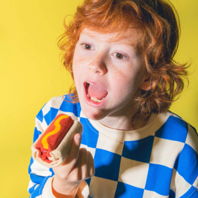 Criança ruiva com camisola azul e branca segurando salsicha de tecido