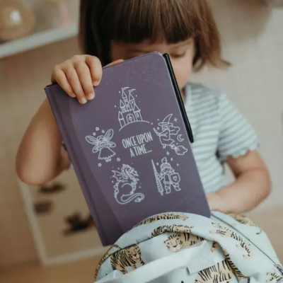 Caderno roxo com desenhos brancos e texto ONCE UPON A TIME... nas mãos de uma criança