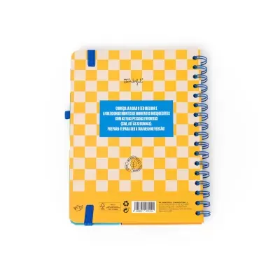 Caderno espiral com padrão xadrez amarelo e bege, elástico azul e texto em azul na capa