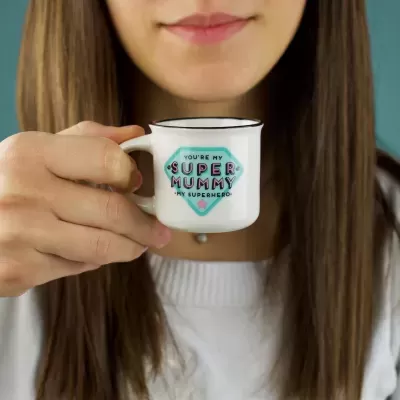 Caneca de metal branca com texto colorido sendo segurada por mulher com cabelo castanho comprido