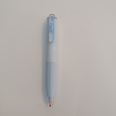 Caneta esferográfica branca com tampa azul clara sobre superfície branca.