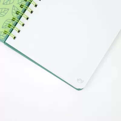 Caderno espiral verde com folhas brancas e ícone pequeno no canto inferior