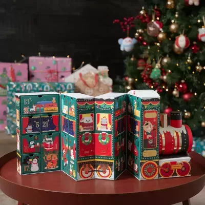 Advento em formato de comboio natalício com gavetas e ilustrações coloridas colocado numa mesa redonda com árvore de Natal ao fundo.