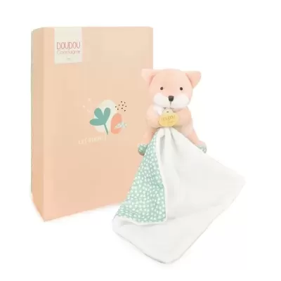 Brinquedo de pelúcia rosa com pano e caixa cor de pêssego com texto da marca.