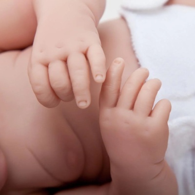 Mãos e barriga de bebé com pele natural e roupa branca