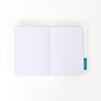 Caderno aberto com capa branca felpuda e páginas brancas