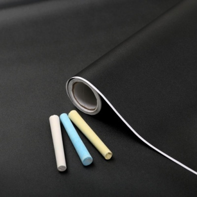 Rolo de quadro-negro preto com giz branco, azul e amarelo ao lado