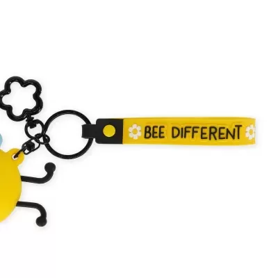 Porta-chaves amarelo e preto com texto BEE DIFFERENT e flores brancas em silicone