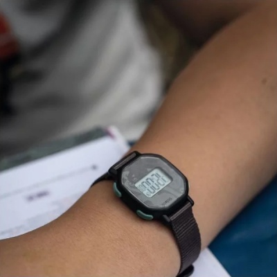 Relógio digital preto com bracelete preta de tecido no pulso de uma pessoa