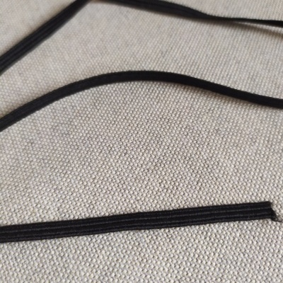 Fitas pretas finas sobre tecido bege com texto 5 mm