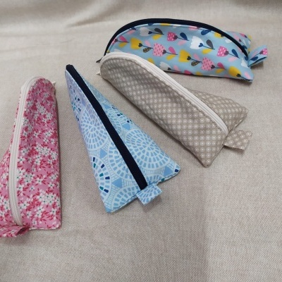 Quatro bolsas de tecido estreitas com padrões variados sobre superfície bege