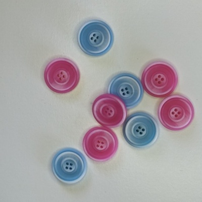 Botões de plástico azuis e cor-de-rosa sobre fundo branco