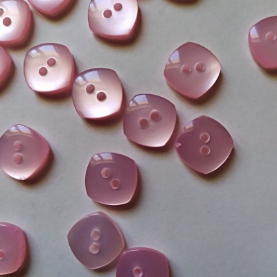 Botões quadrados rosados translúcidos com dois furos sobre fundo branco