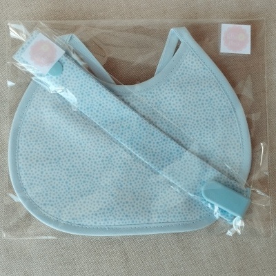 Máscara facial azul clara com padrão pontilhado e tira ajustável embalada em plástico